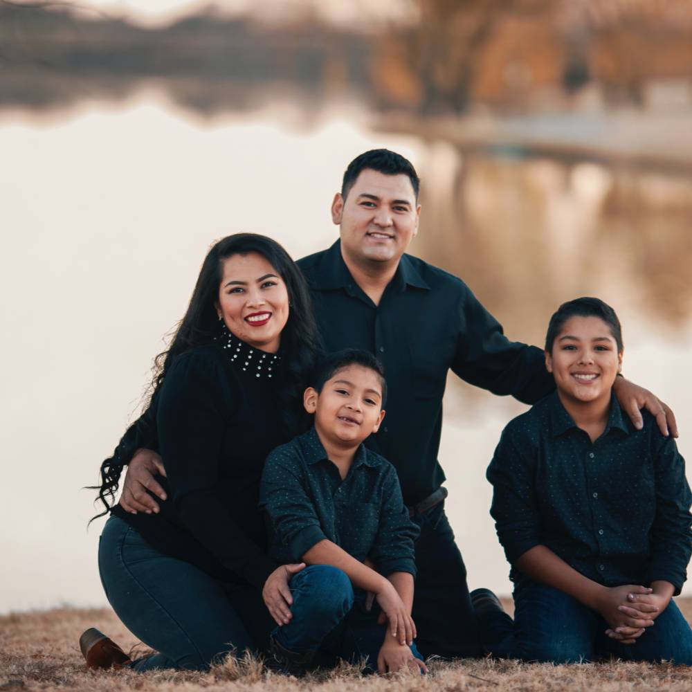 A group of people with two adults and two children posing together smiling at the camera. 