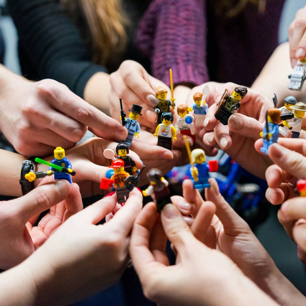 A circle of hands holding lego figures. 